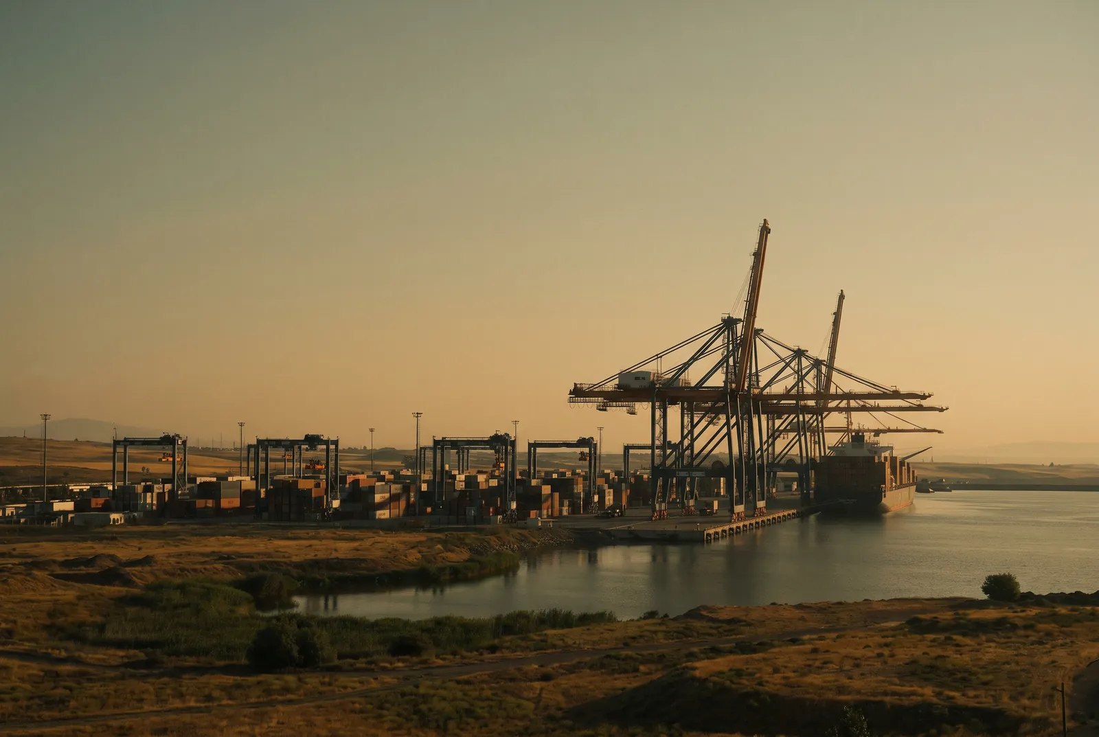 A container port at dawn, cranes and stacked containers